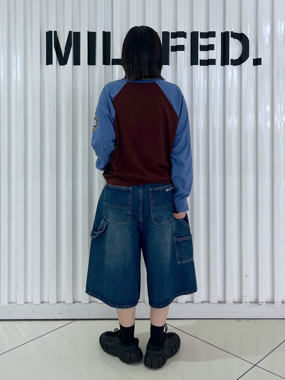 ブラウン系のTシャツ/カットソー、ブルー系のデニムパンツ、ブラック系のショルダーバッグを着用したレディースの秋コーディネートの2枚目の写真