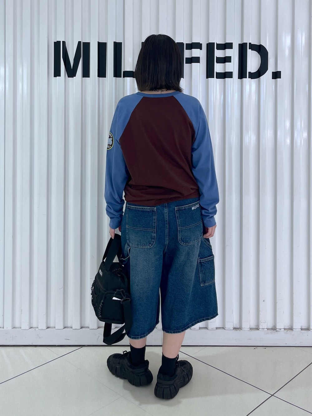 ブラウン系のTシャツ/カットソー、ブルー系のデニムパンツ、ブラック系のショルダーバッグを着用したレディースの秋コーディネートの4枚目の写真
