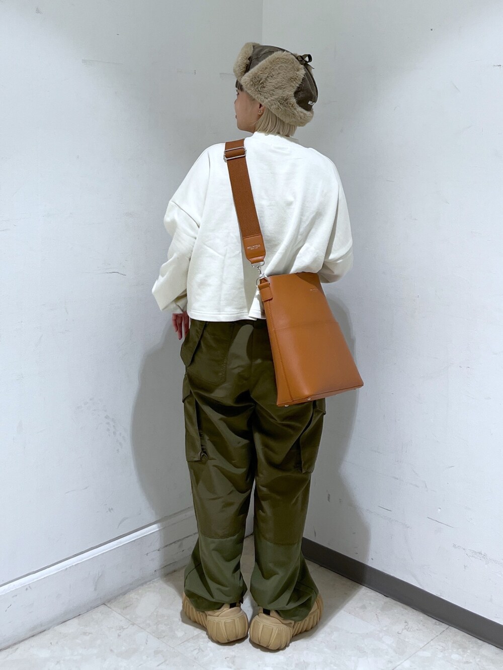 ホワイト系のスウェット、グリーン系のカーゴパンツ、ブラウン系のショルダーバッグを着用したレディースの秋コーディネートの2枚目の写真