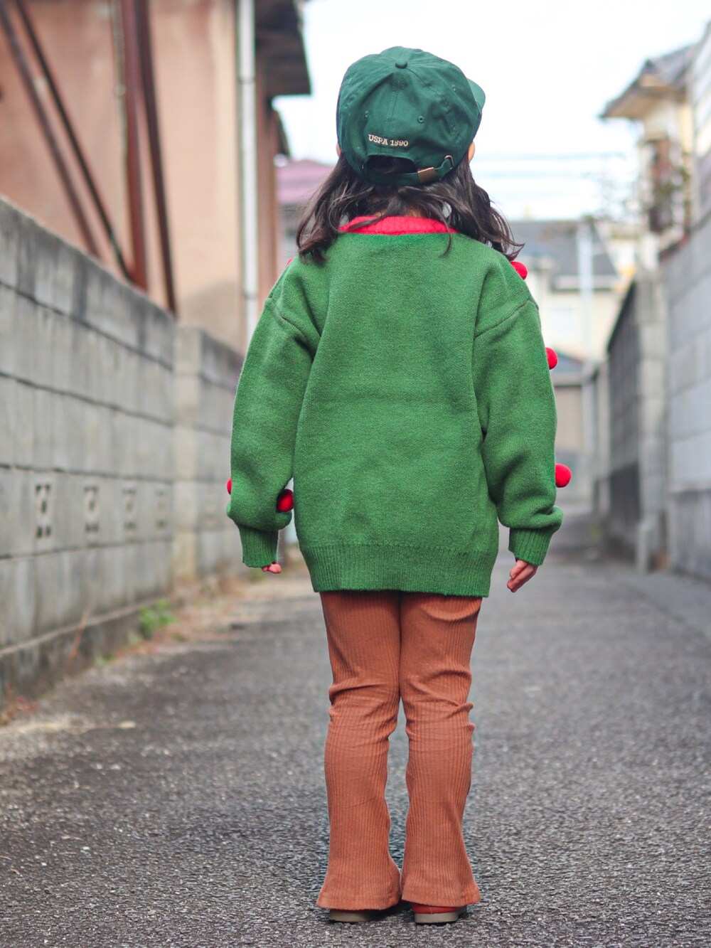 グリーン系のニット/セーター、ベージュ系のその他アウター、ブラウン系のパンツを着用したキッズの冬コーディネートの4枚目の写真