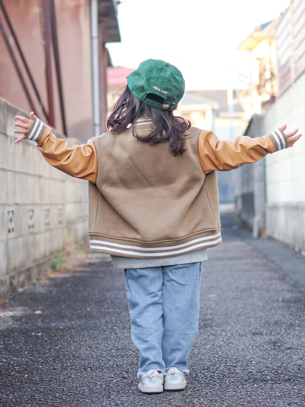 グレー系のスウェット、ベージュ系のスタジャン、ブルー系のデニムパンツを着用したキッズの冬コーディネートの3枚目の写真