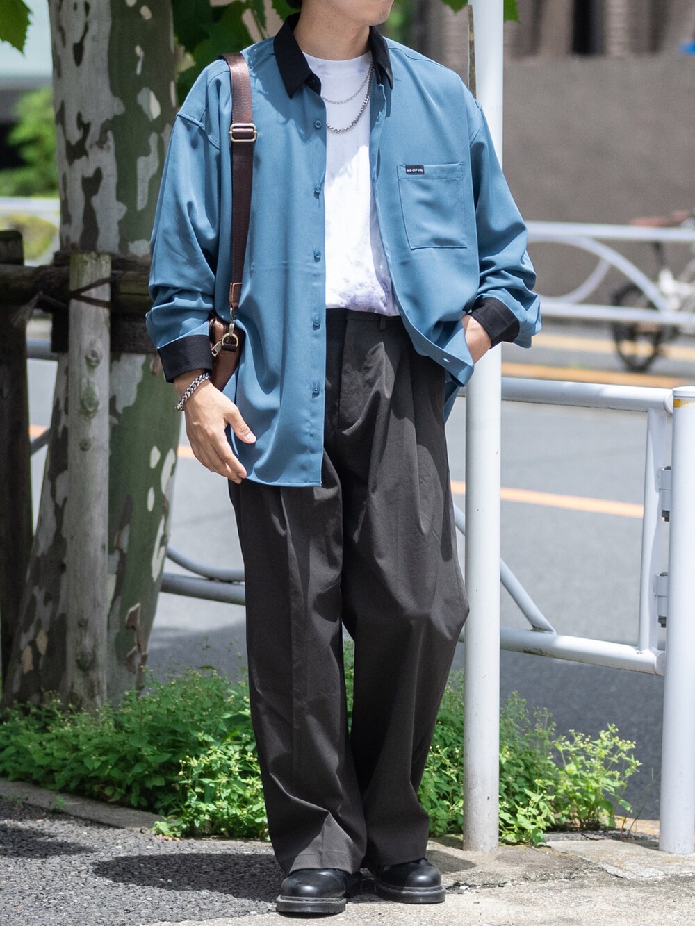 ブラック系のショルダーバッグ、グレー系のスラックス、ブラック系のドレスシューズを着用したメンズの夏コーディネートの3枚目の写真