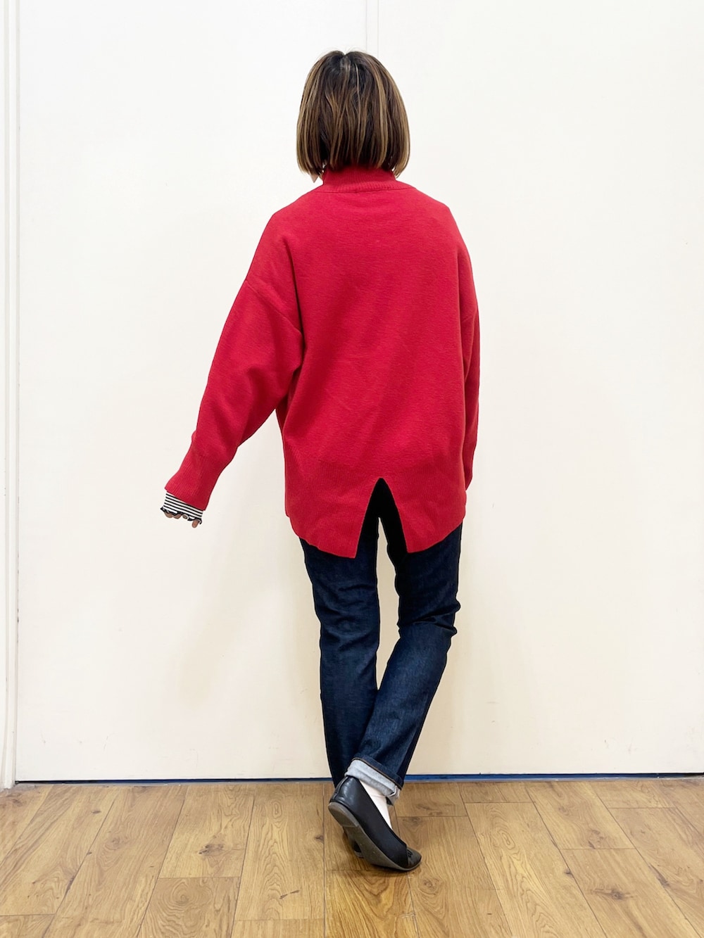 レッド系のニット/セーター、グレー系のハンドバッグ、ブラック系のチェスターコートを着用したレディースの冬コーディネートの3枚目の写真