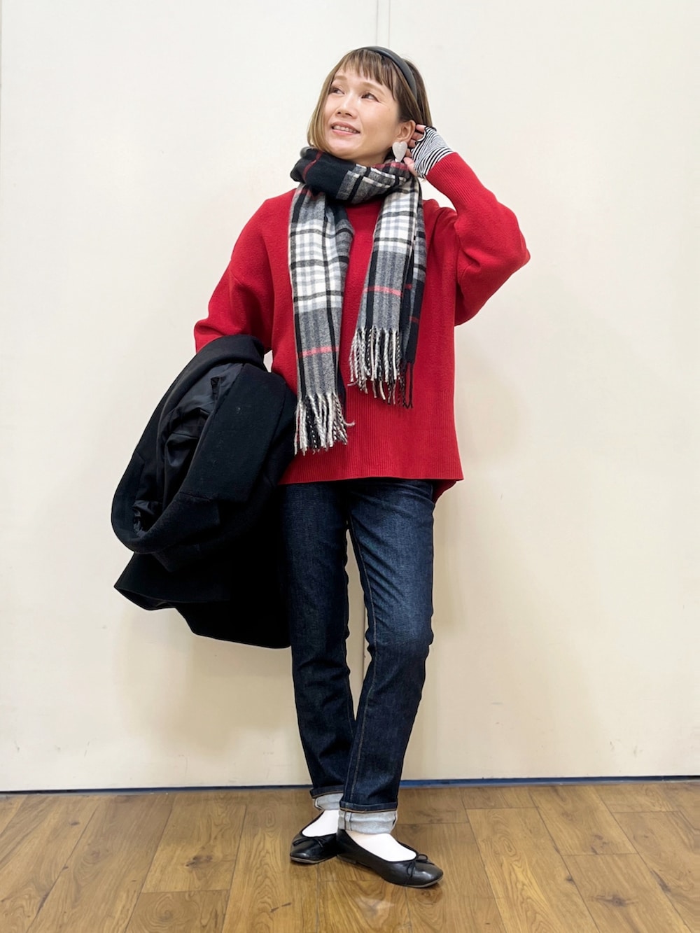 レッド系のニット/セーター、グレー系のハンドバッグ、ブラック系のチェスターコートを着用したレディースの冬コーディネートの2枚目の写真