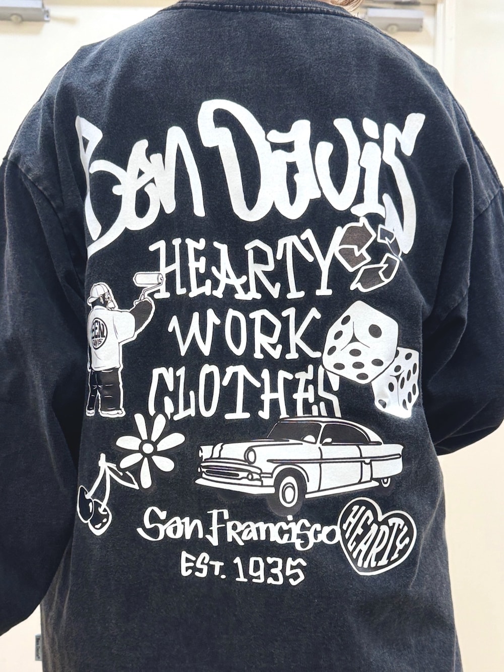 ブラック系のTシャツ/カットソー、ブラック系のバックパック/リュック、ホワイト系のスニーカーを着用したレディースの秋コーディネートの2枚目の写真