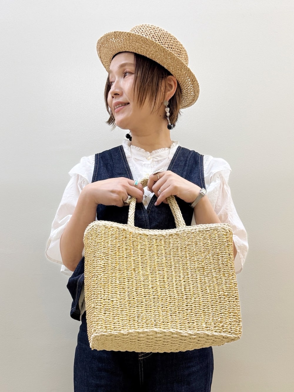 ブラック系のバレエシューズ、ゴールド系のかごバッグ、ブルー系のデニムパンツを着用したレディースの夏コーディネートの5枚目の写真