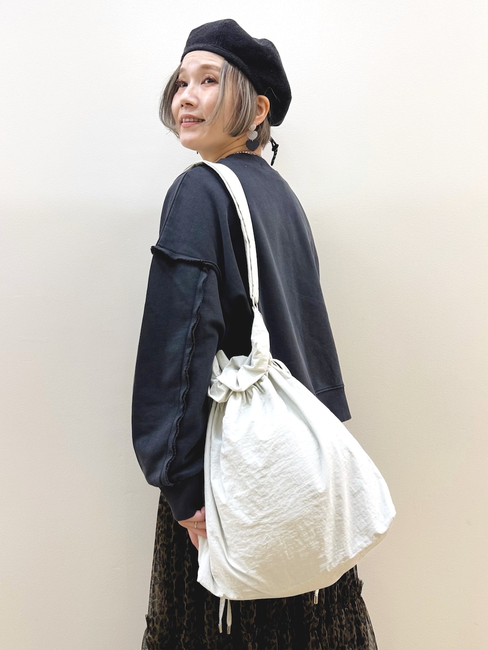 ブラック系のスウェット、ブラウン系のスカート、ホワイト系のショルダーバッグを着用したレディースの秋コーディネートの9枚目の写真