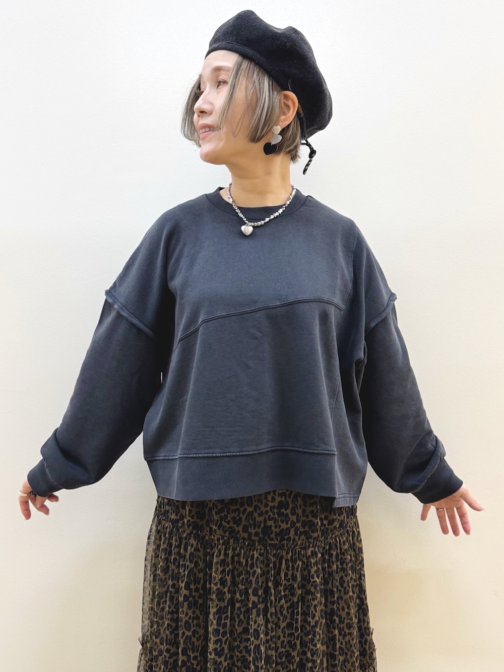 ブラック系のスウェット、ブラウン系のスカート、ホワイト系のショルダーバッグを着用したレディースの秋コーディネートの2枚目の写真