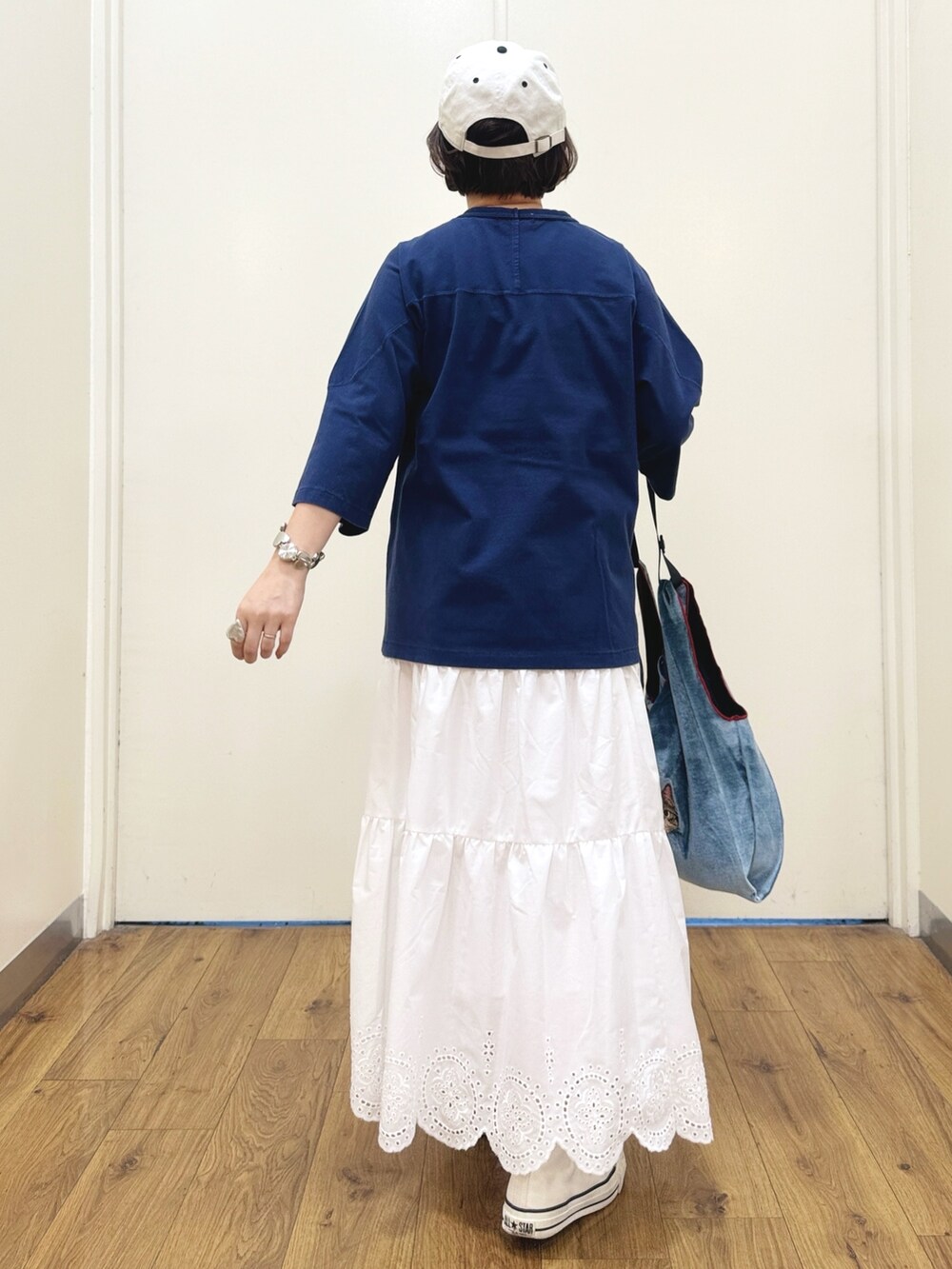 ブルー系のトートバッグ、ホワイト系のスニーカー、ホワイト系のスカートを着用したレディースの秋コーディネートの4枚目の写真
