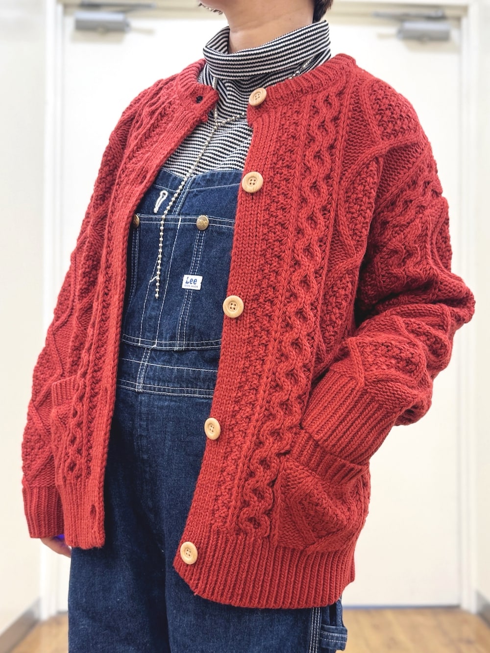 ブルー系のサロペット/オーバーオール、ブラック系のダウンジャケット/コート、レッド系のニット/セーターを着用したレディースの冬コーディネートの3枚目の写真