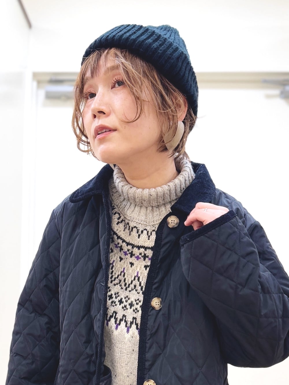 ホワイト系のニット/セーター、ブルー系のデニムパンツ、ブラック系のその他アウターを着用したレディースの冬コーディネートの4枚目の写真