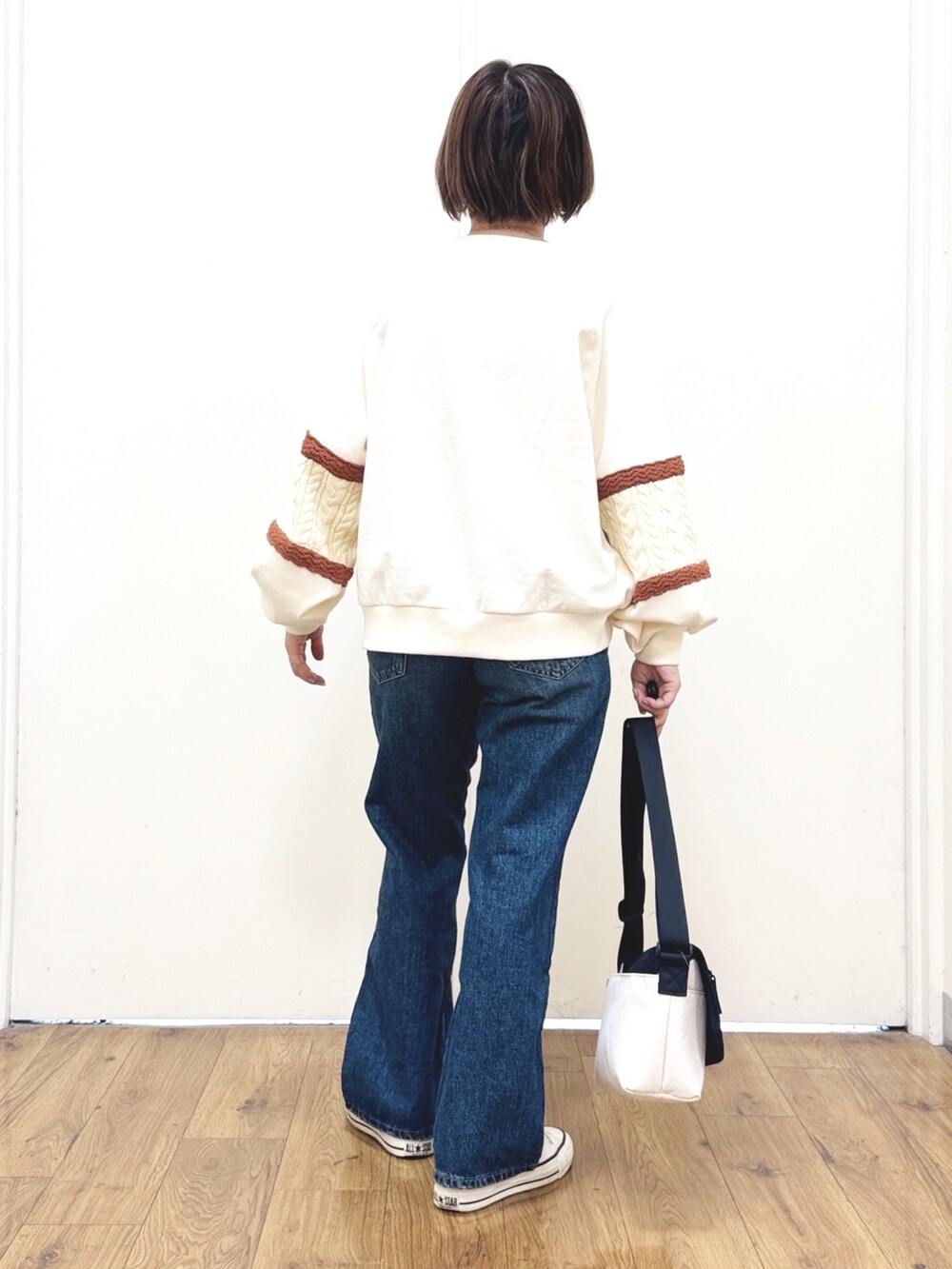 ブルー系のデニムパンツ、ホワイト系のスウェット、ブラック系のショルダーバッグを着用したレディースの冬コーディネートの4枚目の写真