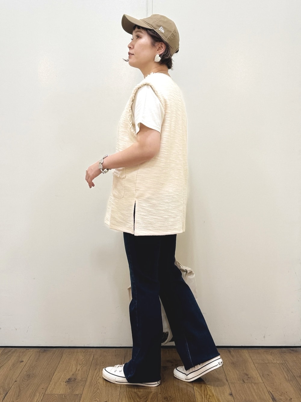 ホワイト系のベスト、ホワイト系のTシャツ/カットソー、ブルー系のデニムパンツを着用したレディースの秋コーディネートの2枚目の写真