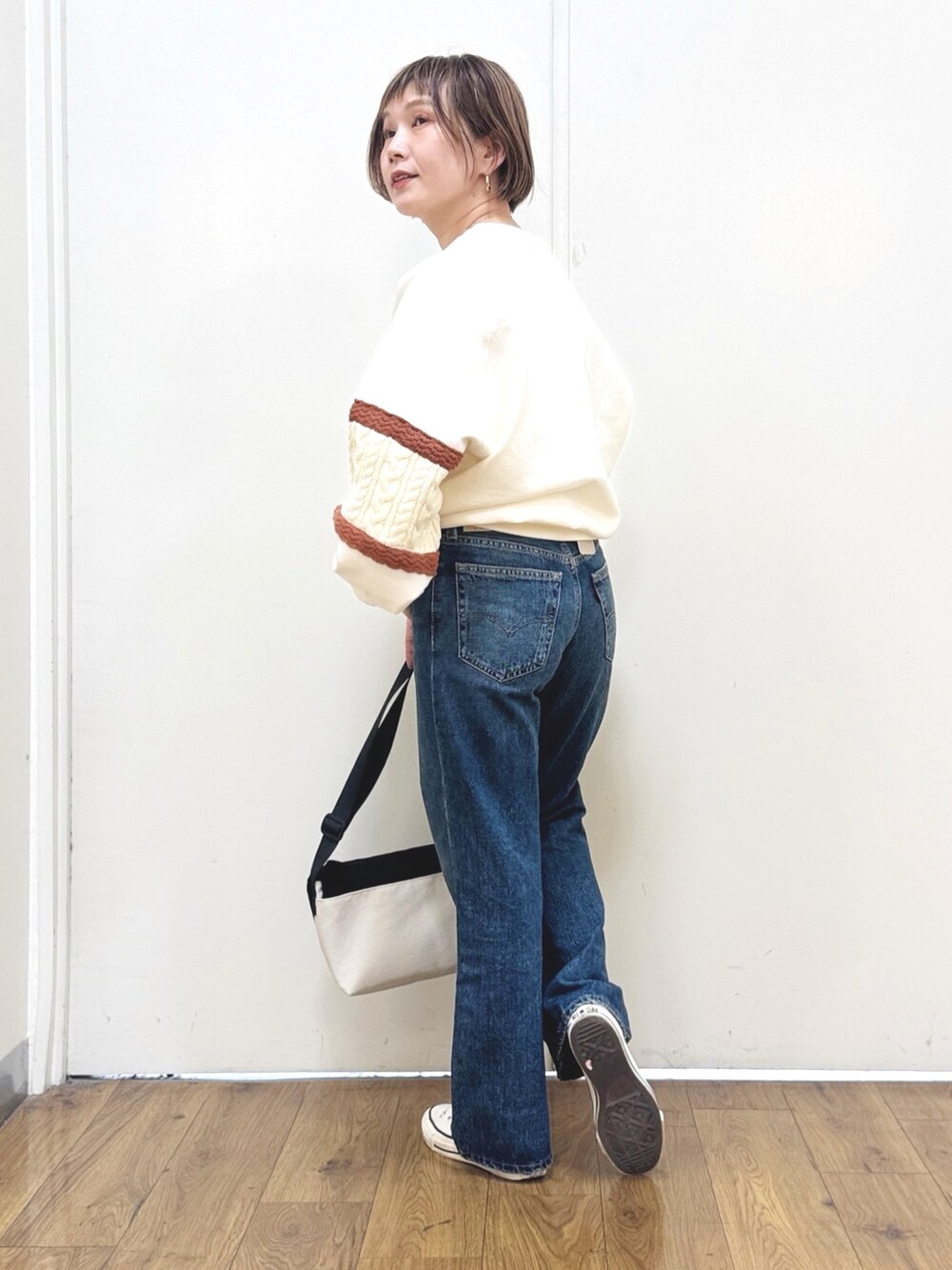 ブルー系のデニムパンツ、ホワイト系のスウェット、ブラック系のショルダーバッグを着用したレディースの冬コーディネートの7枚目の写真