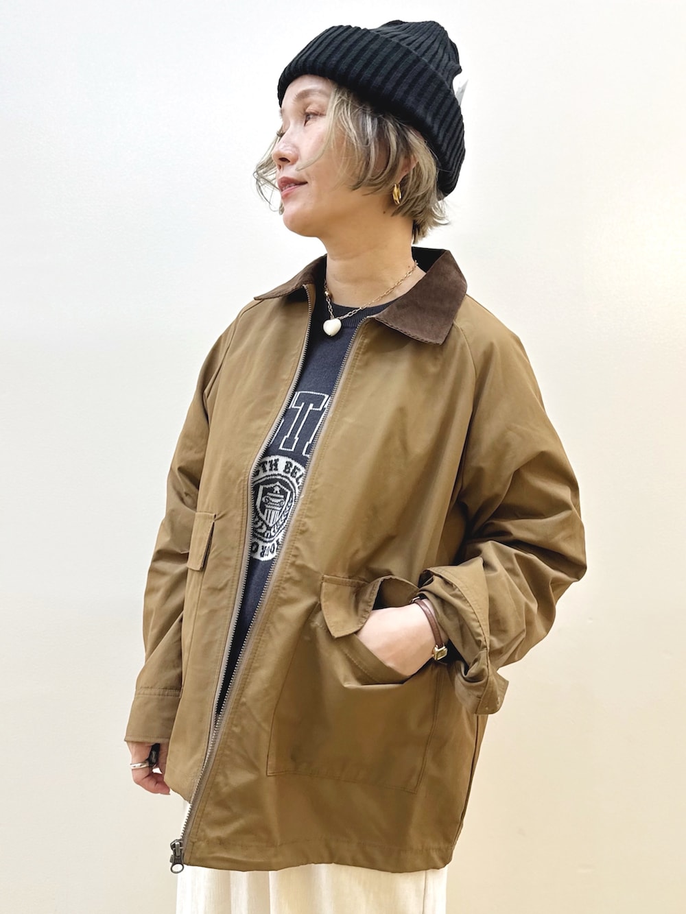 ブラック系のショルダーバッグ、ホワイト系のスカート、ブラック系のニット/セーターを着用したレディースの秋コーディネートの4枚目の写真