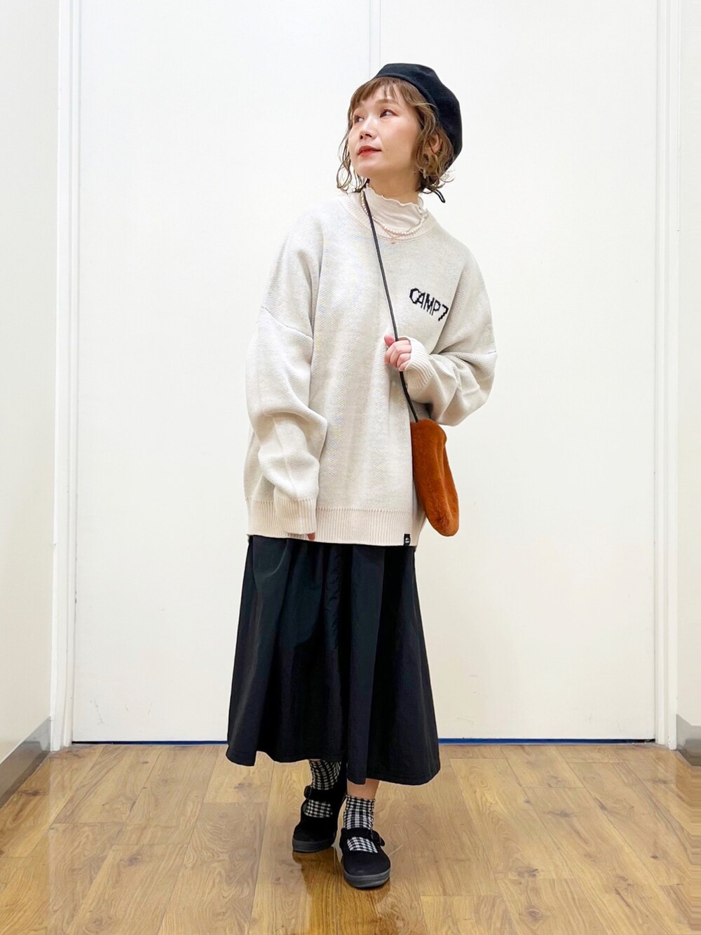 ホワイト系のニット/セーター、ホワイト系のTシャツ/カットソー、ブラック系のスカートを着用したレディースの秋コーディネートの2枚目の写真