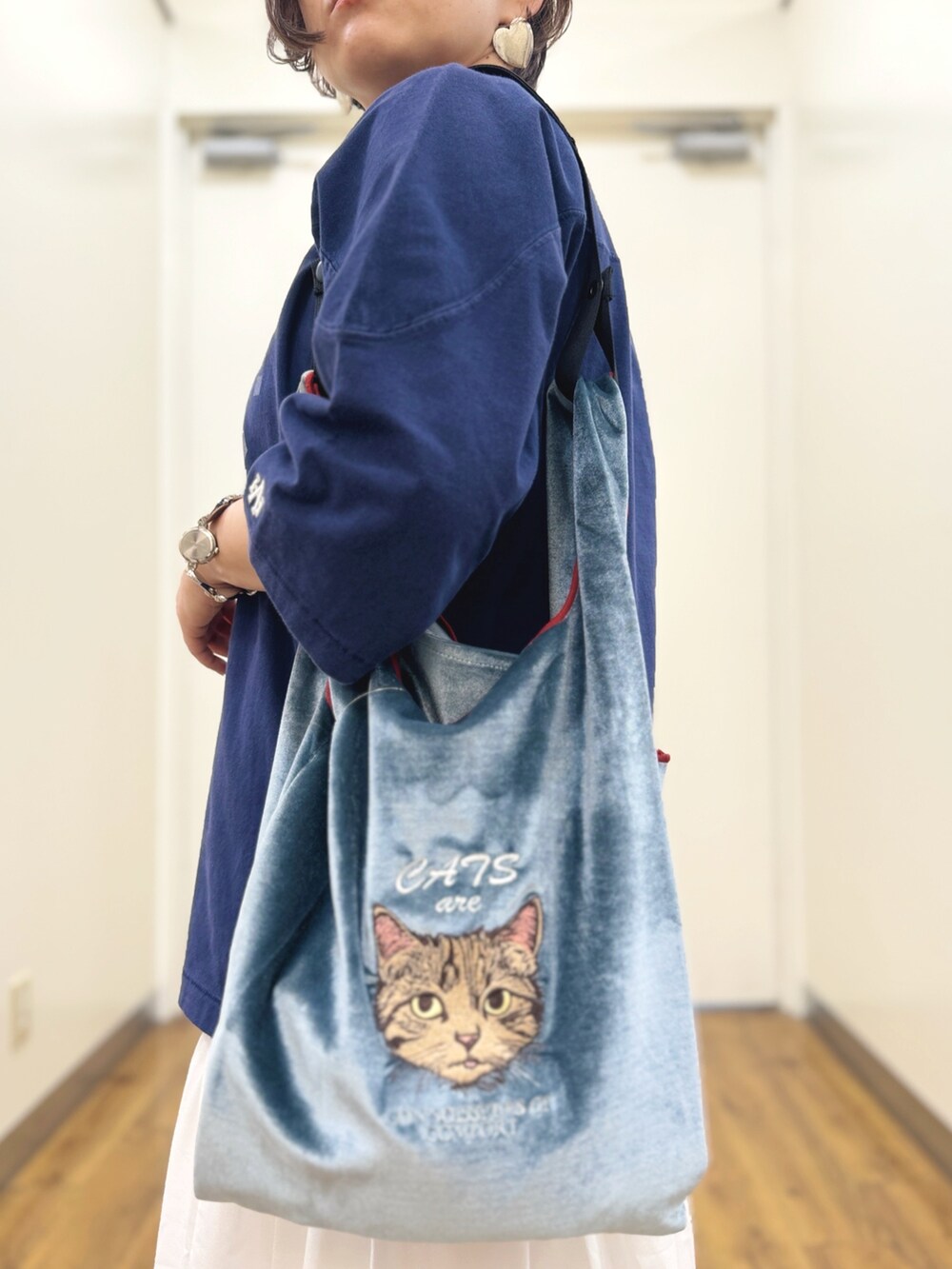 ブルー系のトートバッグ、ホワイト系のスニーカー、ホワイト系のスカートを着用したレディースの秋コーディネートの3枚目の写真