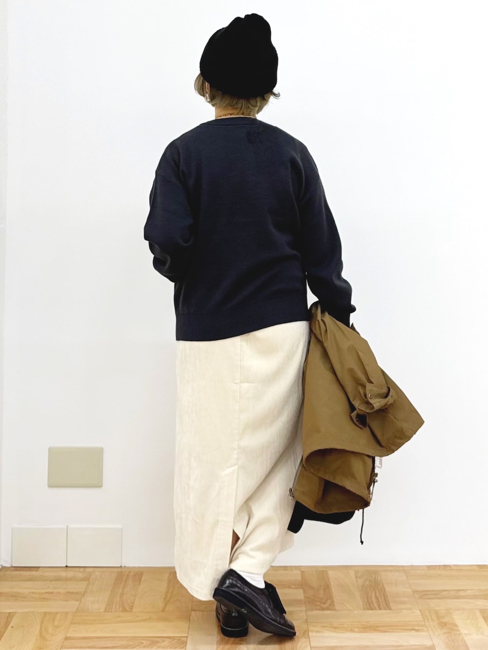 ブラック系のショルダーバッグ、ホワイト系のスカート、ブラック系のニット/セーターを着用したレディースの秋コーディネートの9枚目の写真