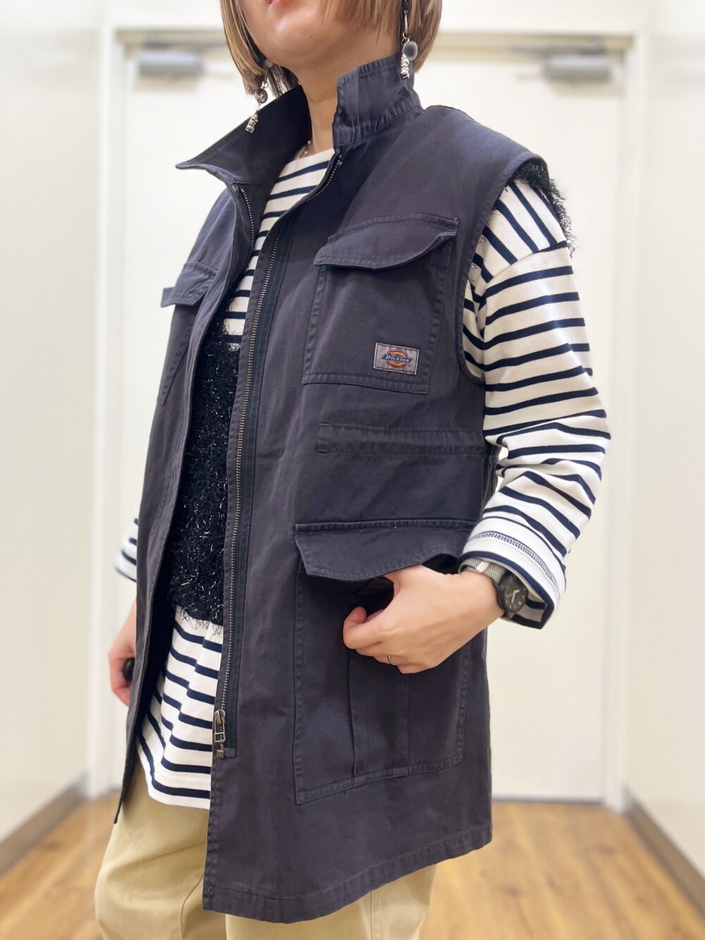 ベージュ系のチノパンツ、ブラック系のベスト、ブルー系のTシャツ/カットソーを着用したレディースの冬コーディネートの4枚目の写真