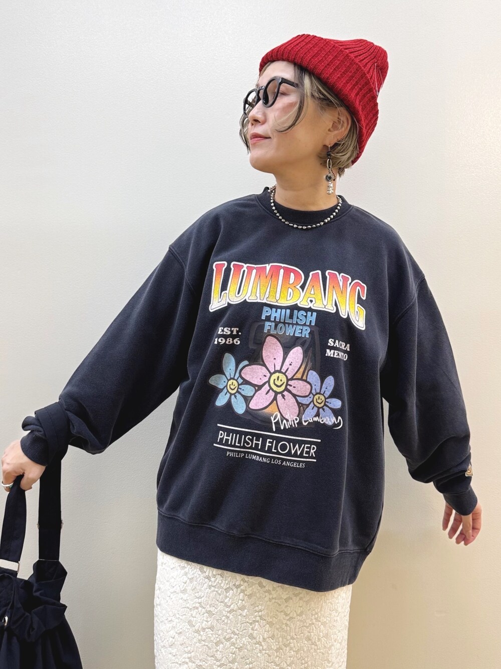 ホワイト系のスカート、ブラック系のスニーカー、ブラック系のショルダーバッグを着用したレディースの秋コーディネートの3枚目の写真