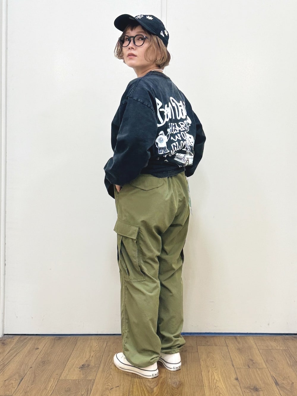 ブラック系のTシャツ/カットソー、ブラック系のバックパック/リュック、ホワイト系のスニーカーを着用したレディースの秋コーディネートの8枚目の写真