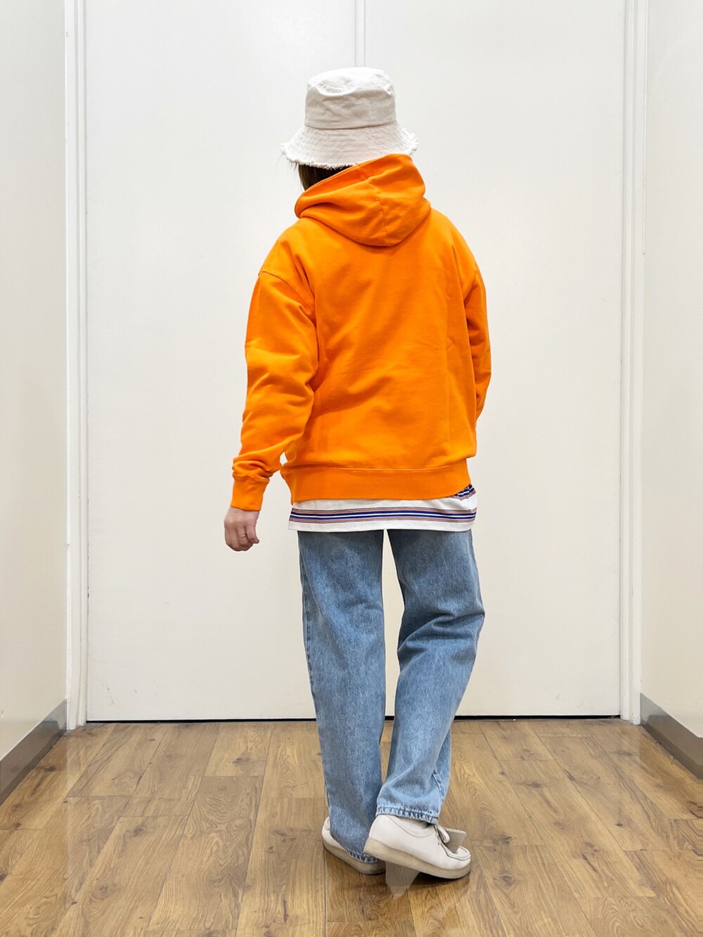 ブルー系のデニムパンツ、オレンジ系のパーカー、ホワイト系のTシャツ/カットソーを着用したレディースの冬コーディネートの3枚目の写真
