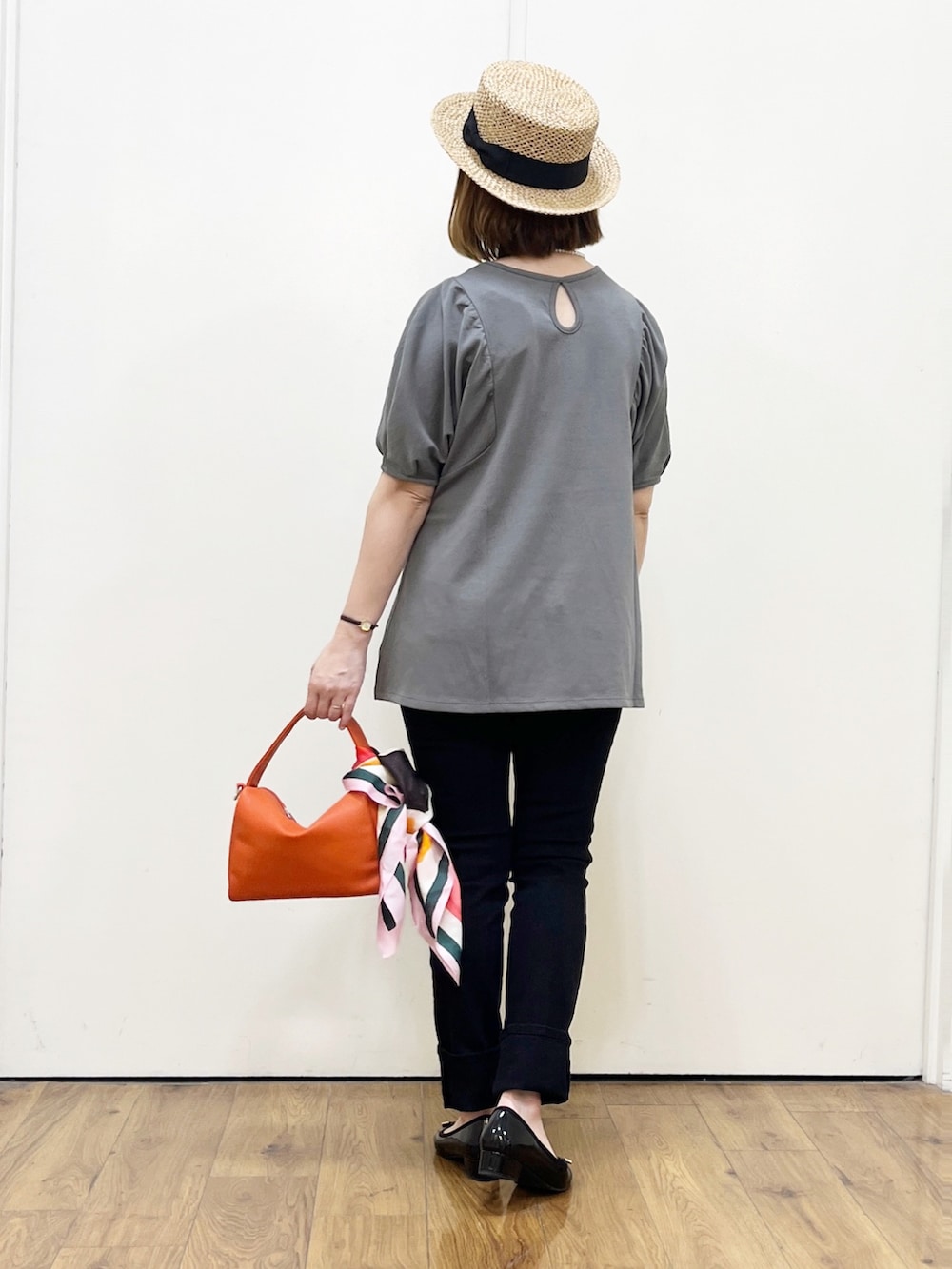 グレー系のTシャツ/カットソー、オレンジ系のハンドバッグ、ブラック系のその他パンツを着用したレディースの春コーディネートの3枚目の写真