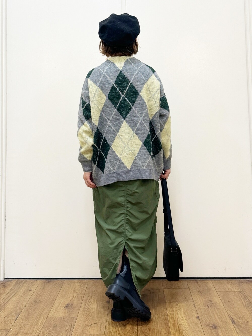 グリーン系のスカート、ブラック系のショルダーバッグ、グリーン系のカーディガン/ボレロを着用したレディースの秋コーディネートの3枚目の写真