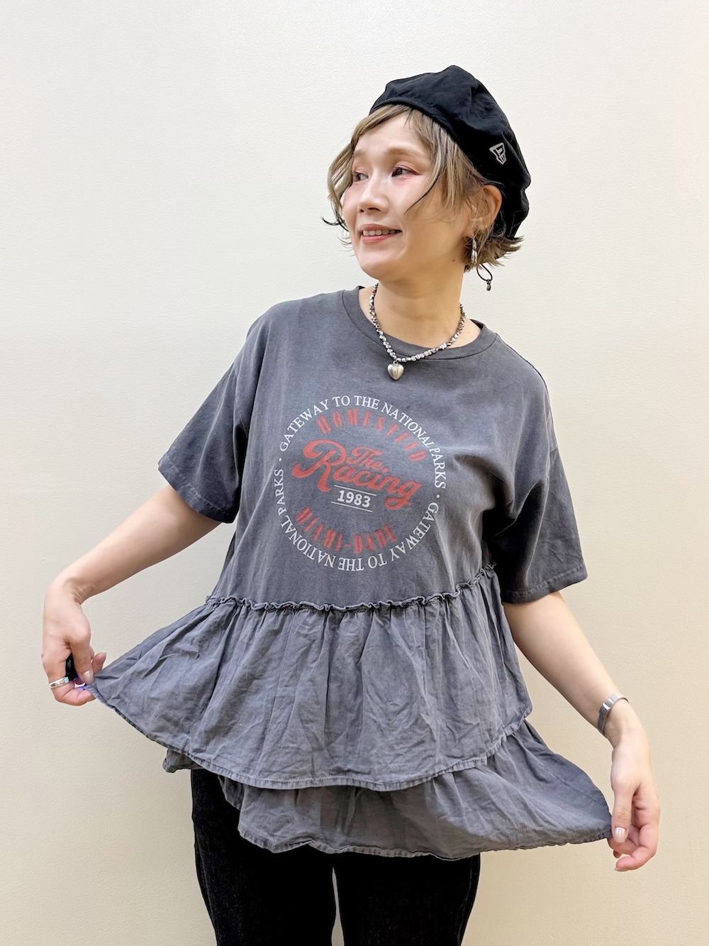 グレー系のTシャツ/カットソー、ホワイト系のスカート、ブラック系のデニムパンツを着用したレディースの春コーディネートの2枚目の写真