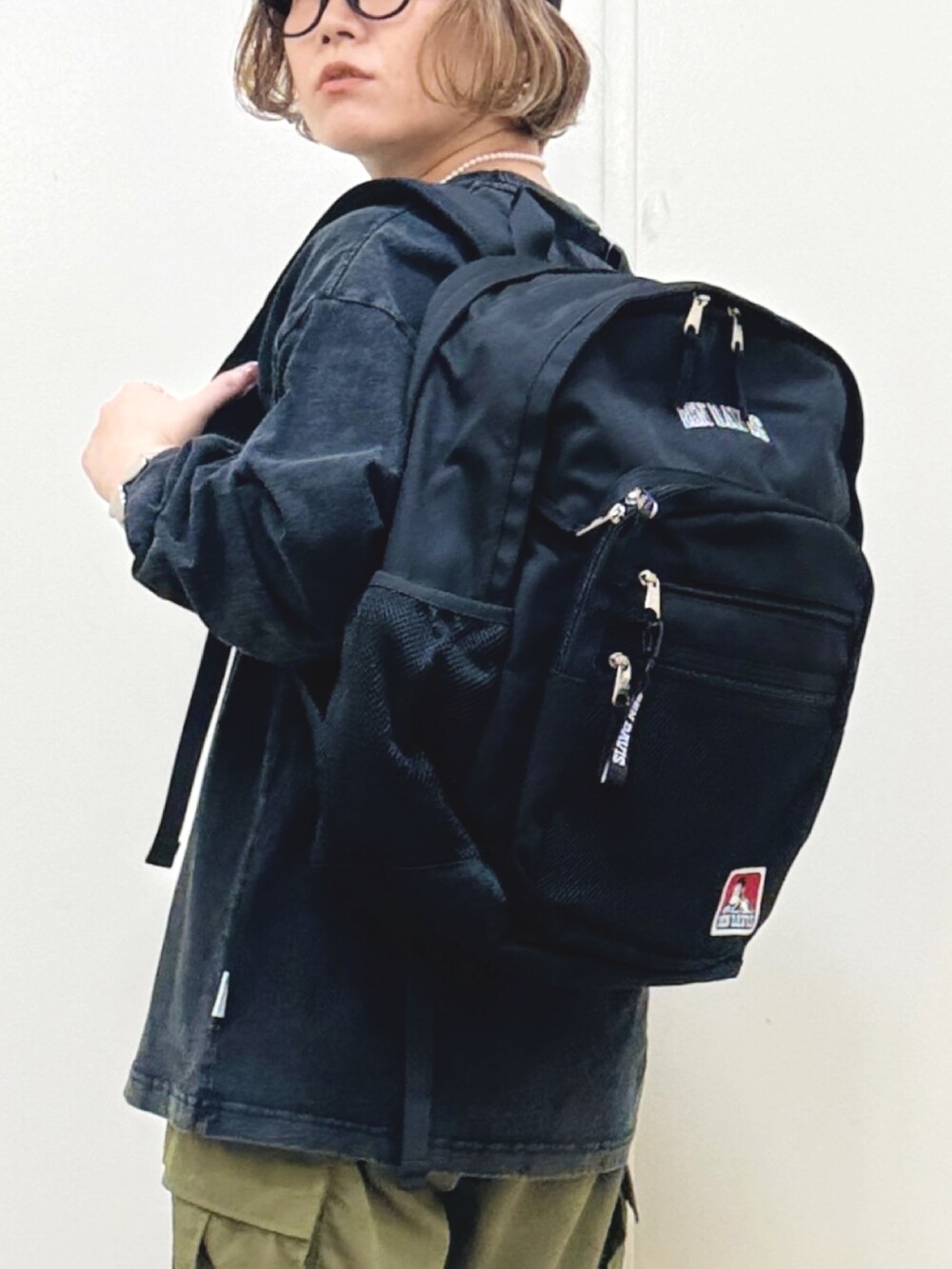 ブラック系のTシャツ/カットソー、ブラック系のバックパック/リュック、ホワイト系のスニーカーを着用したレディースの秋コーディネートの6枚目の写真