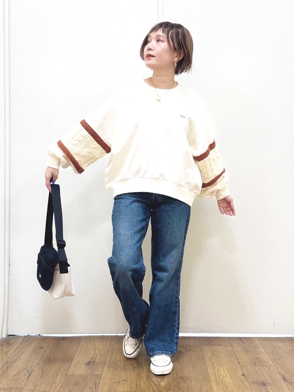 ブルー系のデニムパンツ、ホワイト系のスウェット、ブラック系のショルダーバッグを着用したレディースの冬コーディネートの5枚目の写真