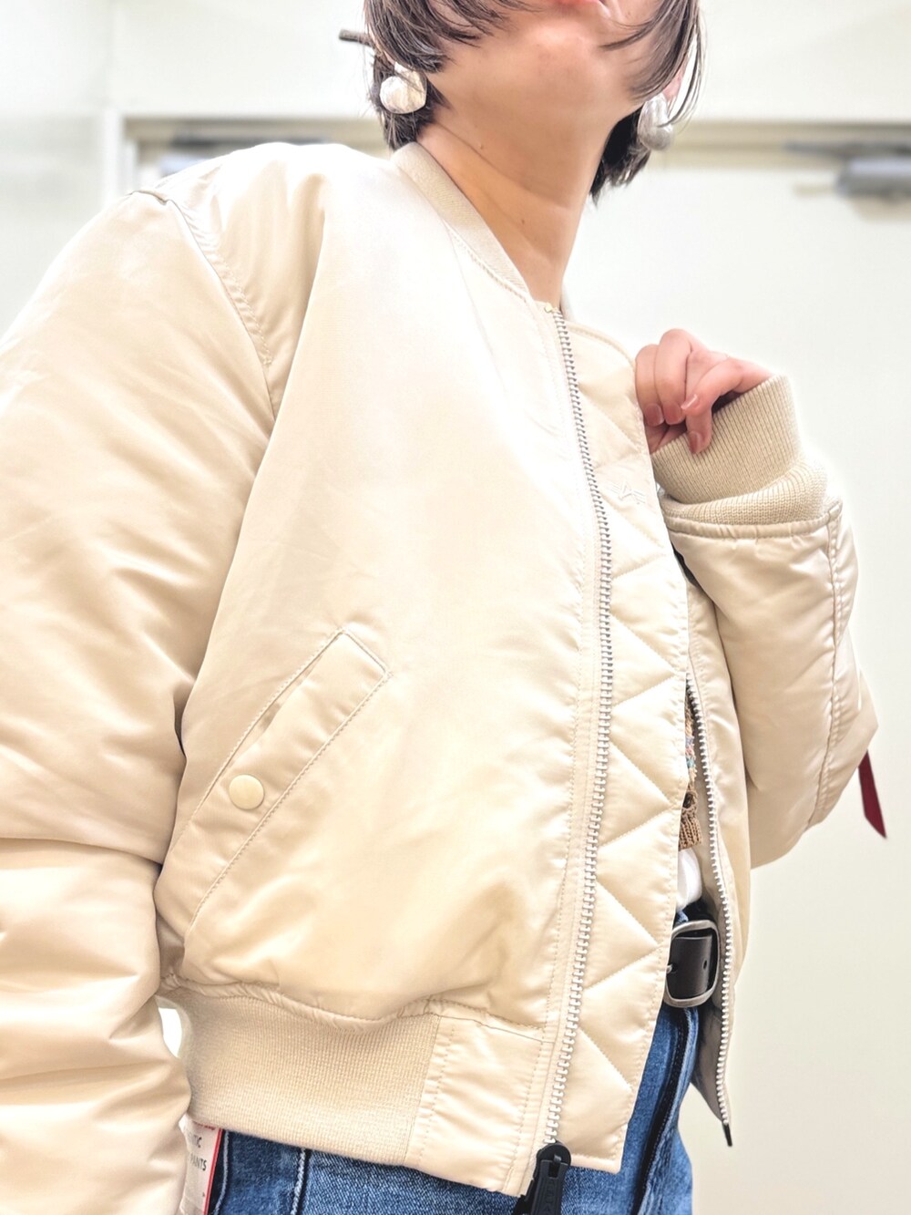 ホワイト系のMA-1、ブルー系のデニムパンツ、ブラウン系のアンサンブルを着用したレディースの秋コーディネートの4枚目の写真