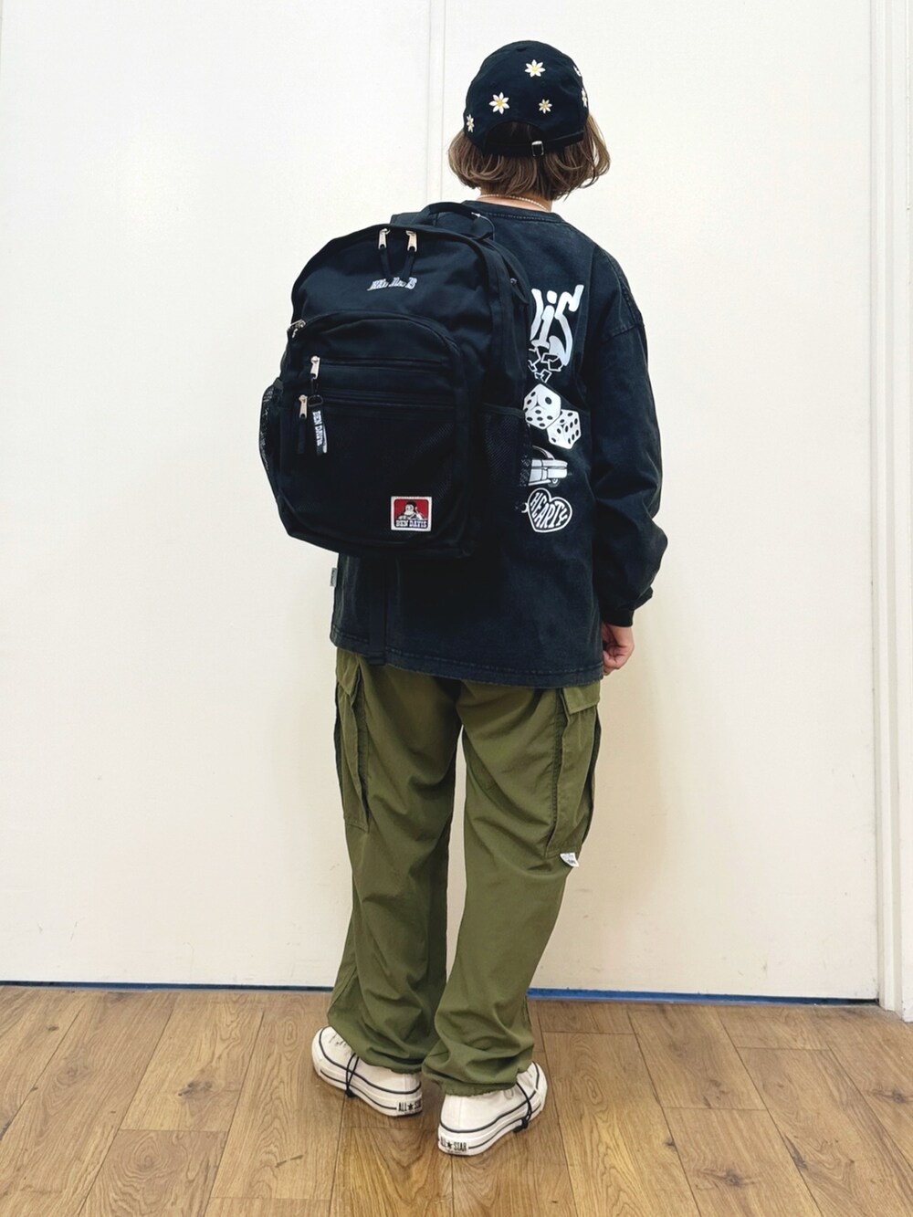 ブラック系のTシャツ/カットソー、ブラック系のバックパック/リュック、ホワイト系のスニーカーを着用したレディースの秋コーディネートの5枚目の写真