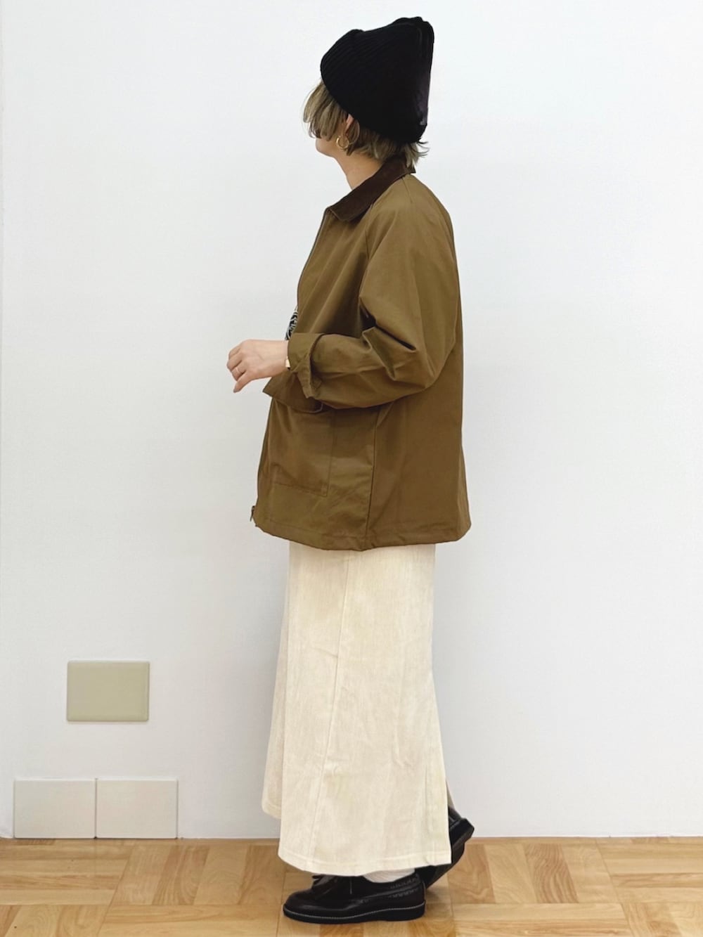 ブラック系のショルダーバッグ、ホワイト系のスカート、ブラック系のニット/セーターを着用したレディースの秋コーディネートの3枚目の写真