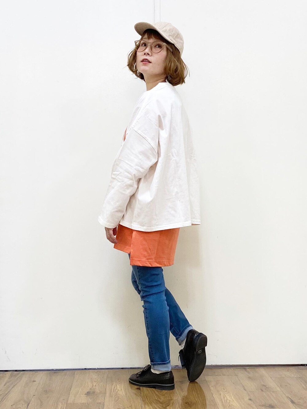 オレンジ系のTシャツ/カットソー、ブラック系のショルダーバッグ、ブルー系のデニムパンツを着用したレディースの冬コーディネートの3枚目の写真