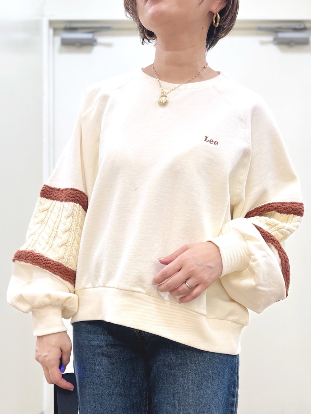 ブルー系のデニムパンツ、ホワイト系のスウェット、ブラック系のショルダーバッグを着用したレディースの冬コーディネートの2枚目の写真