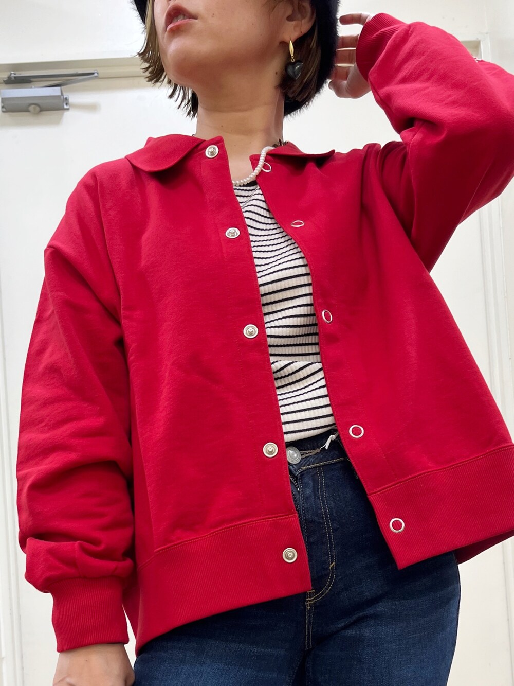 ブラック系のショルダーバッグ、ブルー系のデニムパンツ、レッド系のカーディガン/ボレロを着用したレディースの秋コーディネートの5枚目の写真