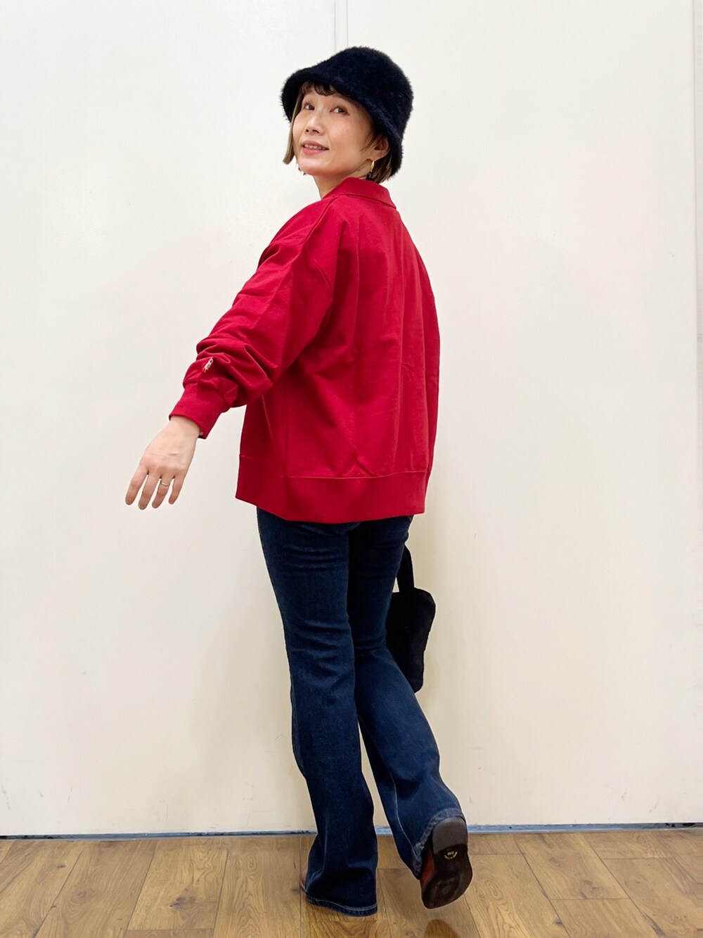 ブラック系のショルダーバッグ、ブルー系のデニムパンツ、レッド系のカーディガン/ボレロを着用したレディースの秋コーディネートの3枚目の写真
