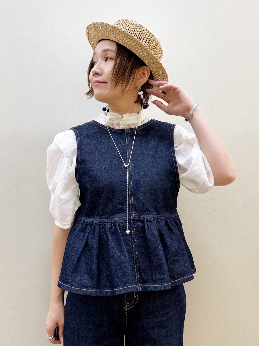 ブラック系のバレエシューズ、ゴールド系のかごバッグ、ブルー系のデニムパンツを着用したレディースの夏コーディネートの4枚目の写真