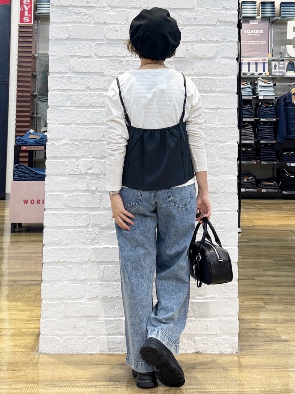 ブラック系のショルダーバッグ、ブラック系のその他シューズ、ブルー系のデニムパンツを着用したレディースの秋コーディネートの3枚目の写真