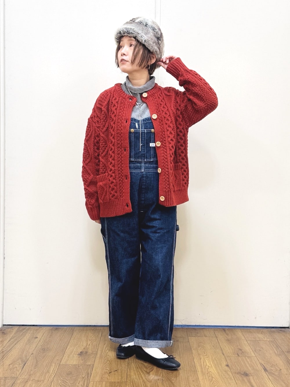 ブルー系のサロペット/オーバーオール、ブラック系のダウンジャケット/コート、レッド系のニット/セーターを着用したレディースの冬コーディネートの2枚目の写真