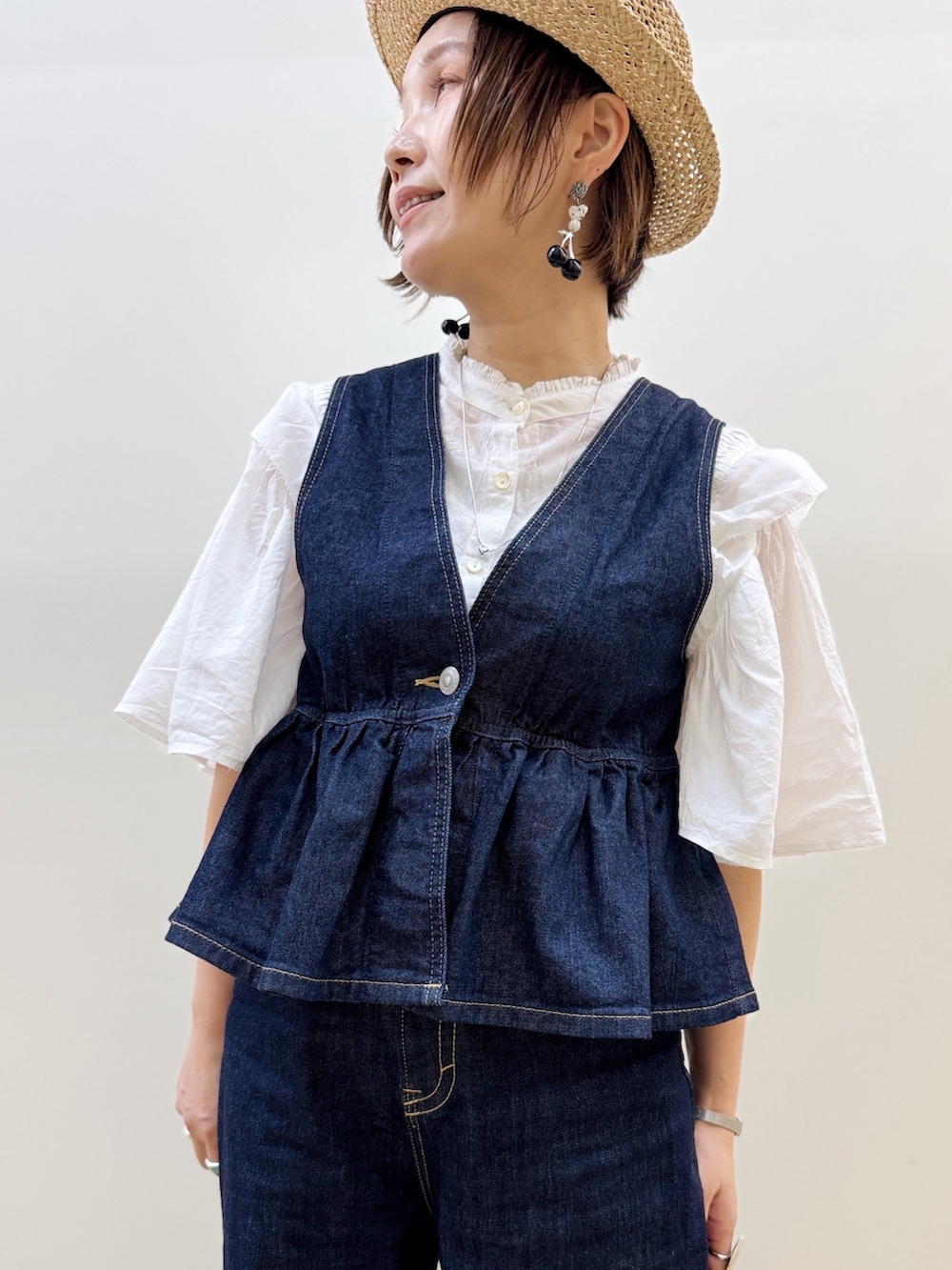 ブラック系のバレエシューズ、ゴールド系のかごバッグ、ブルー系のデニムパンツを着用したレディースの夏コーディネートの2枚目の写真