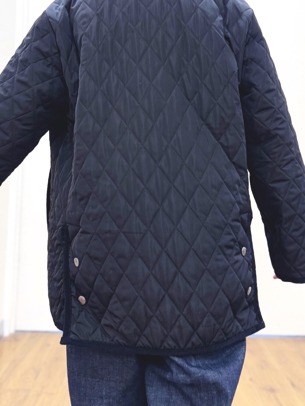 ホワイト系のニット/セーター、ブルー系のデニムパンツ、ブラック系のその他アウターを着用したレディースの冬コーディネートの6枚目の写真