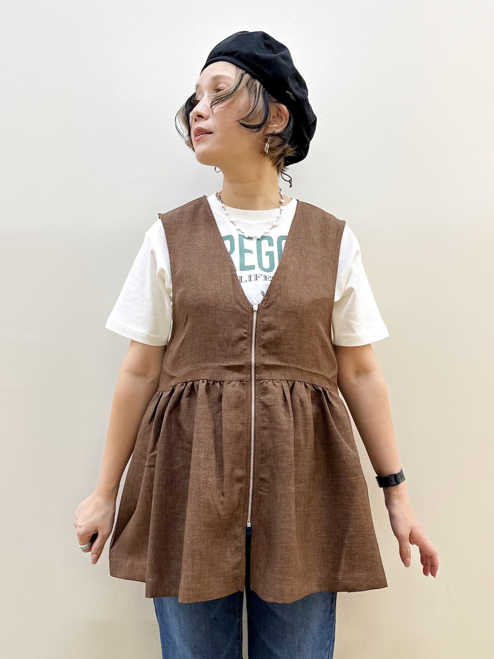 ブルー系のデニムパンツ、ホワイト系のTシャツ/カットソー、ブラウン系のベストを着用したレディースの夏コーディネートの2枚目の写真