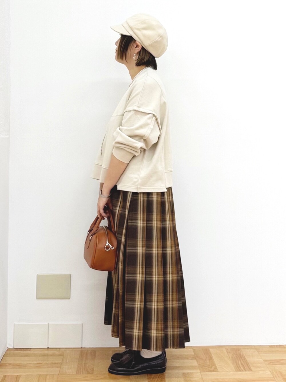 ベージュ系のスウェット、イエロー系のスカート、イエロー系のショルダーバッグを着用したレディースの秋コーディネートの3枚目の写真