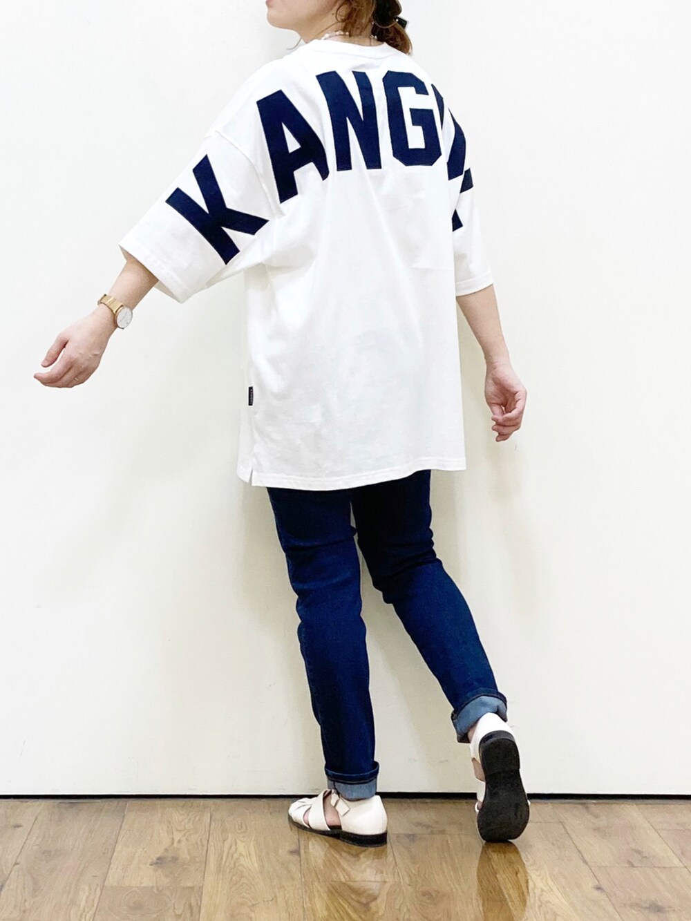 ブルー系のデニムパンツ、ホワイト系のサンダル、ホワイト系のTシャツ/カットソーを着用したレディースの春コーディネートの2枚目の写真