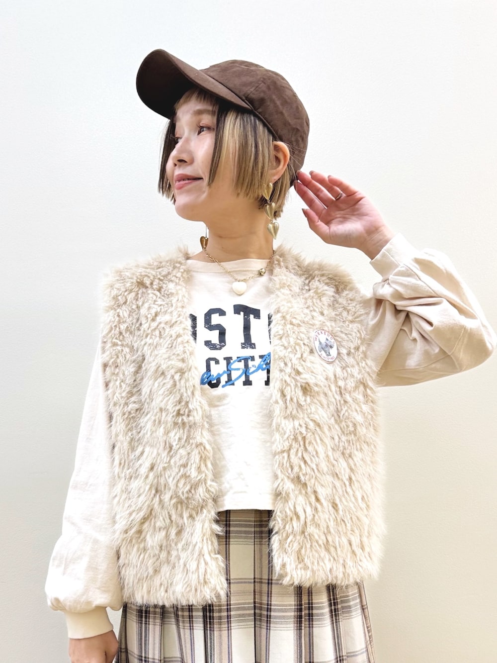 ベージュ系のベスト、ベージュ系のTシャツ/カットソー、ベージュ系のスカートを着用したレディースの秋コーディネートの2枚目の写真