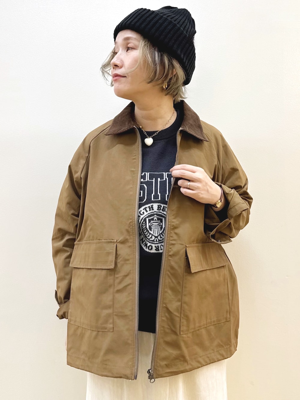 ブラック系のショルダーバッグ、ホワイト系のスカート、ブラック系のニット/セーターを着用したレディースの秋コーディネートの2枚目の写真