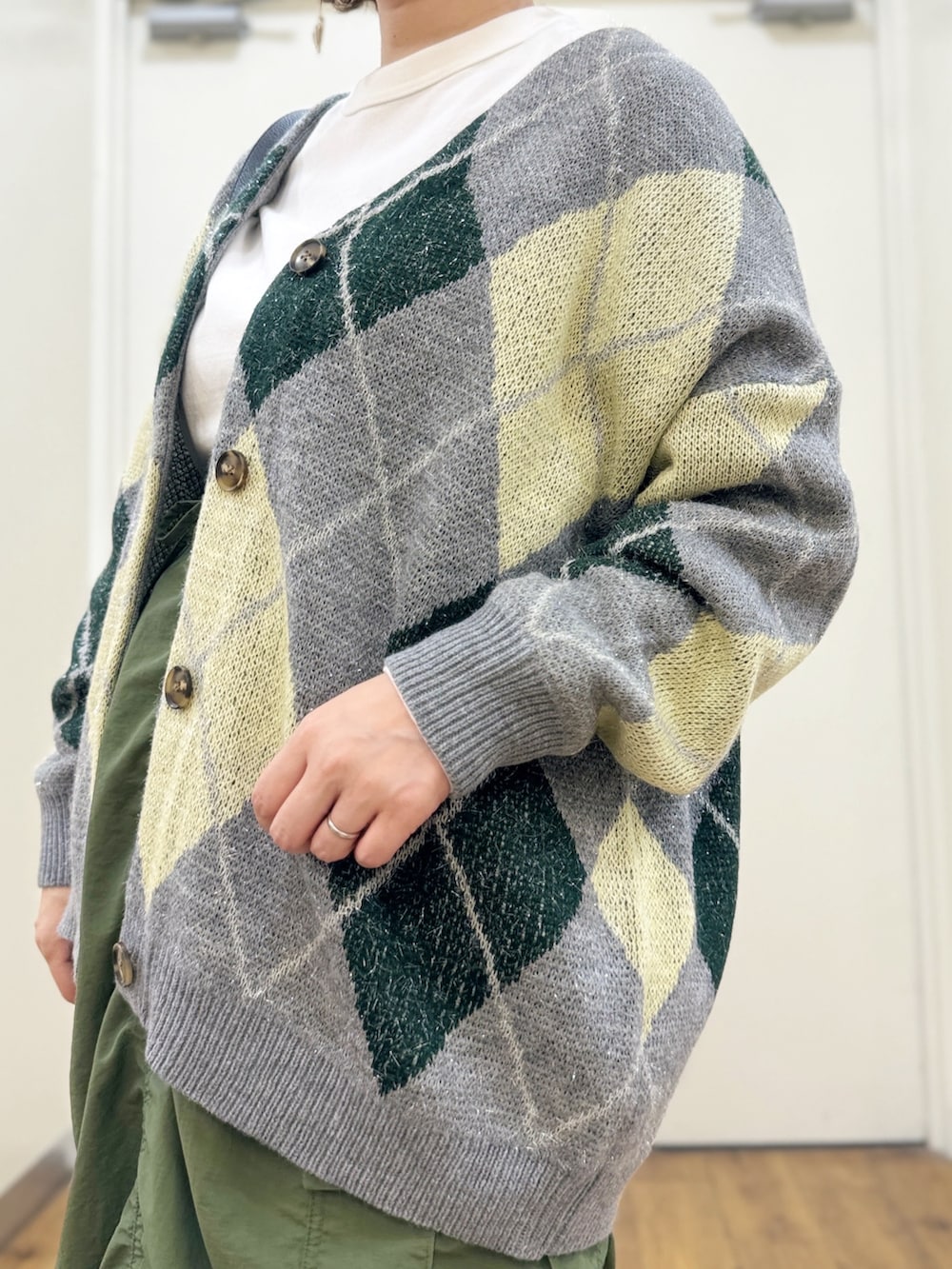 グリーン系のスカート、ブラック系のショルダーバッグ、グリーン系のカーディガン/ボレロを着用したレディースの秋コーディネートの2枚目の写真