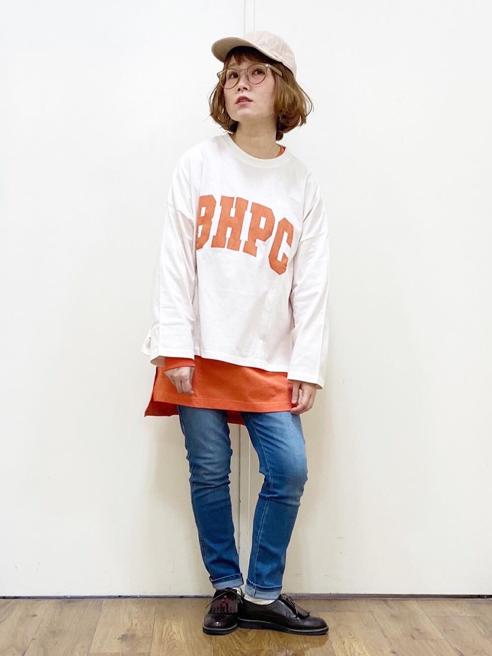 オレンジ系のTシャツ/カットソー、ブラック系のショルダーバッグ、ブルー系のデニムパンツを着用したレディースの冬コーディネートの2枚目の写真